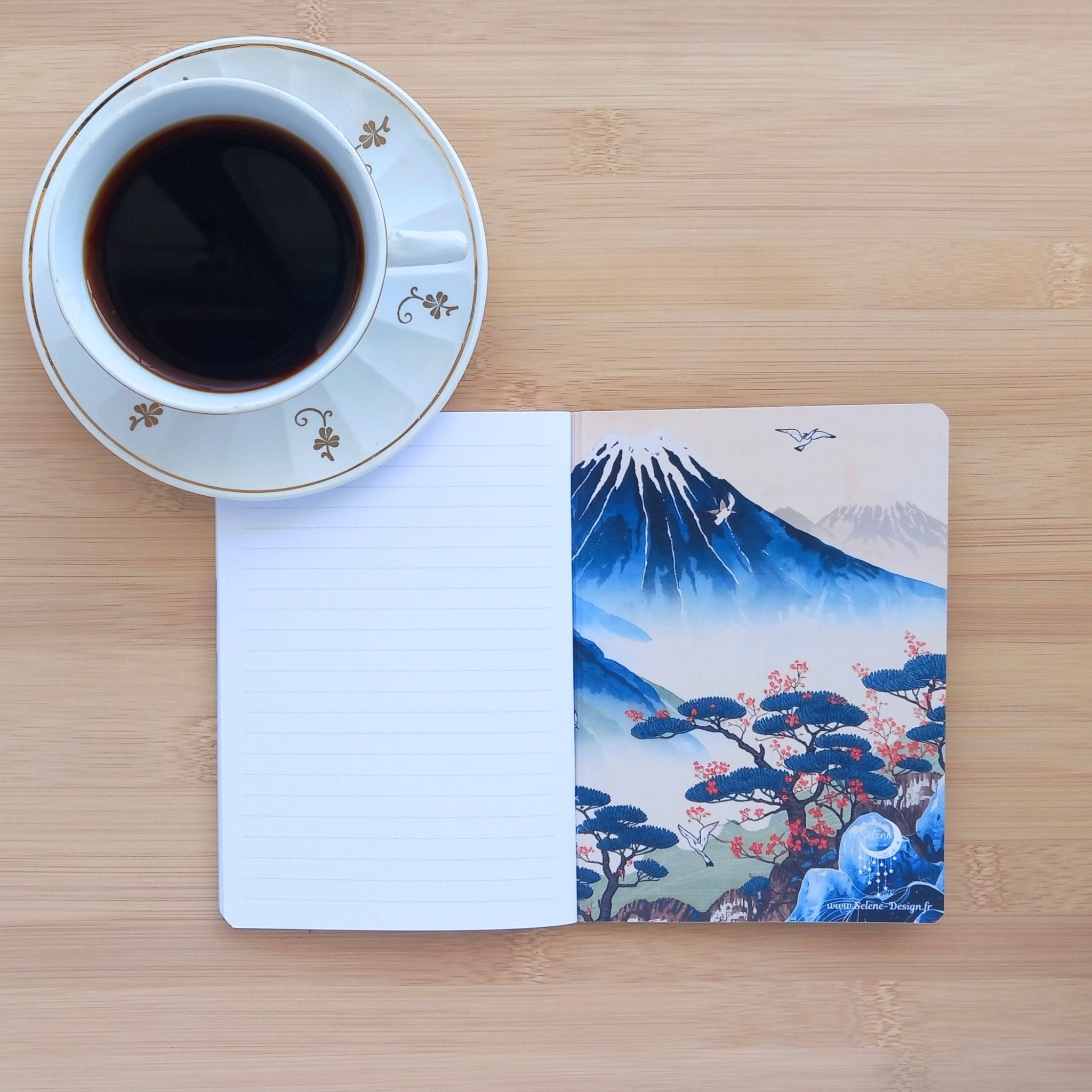 Vue de la couverture intérieure avant du carnet A6 "Bonsaï d'Orient", dévoilant la qualité du papier à l'intérieur. La page de garde de droite révèle une illustration détaillée d'inspiration estampe japonaise, représentant le Mont Fuji, des pins avec des fleurs rose-rouge, et des grues en vol sur un paysage brumeux.