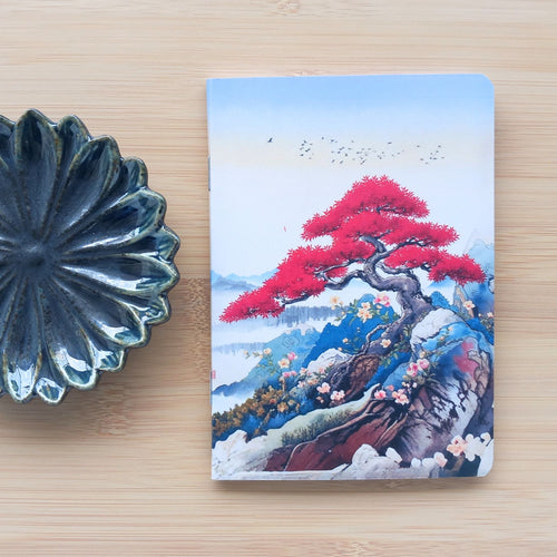 Première de couverture du carnet de notes fait main. Illustration style estampe japonaise (Ukiyo-e) avec un panorama de montagnes bleutées et un premier plan d'arbres en fleurs rouge vermillon.