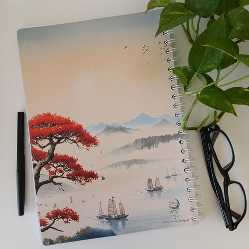 Dos du carnet A4 fait main, paysage oriental au ciel pastel orangé, jonques à voile flottant sur une mer brumeuse, montagnes embrumées à l'horizon et pin aux feuilles rouge vermillon, logo Sélène Design visible.